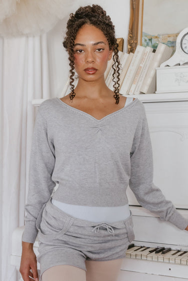 Woman wearing a gray Luna Luna loungewear set standing in a room with a piano.