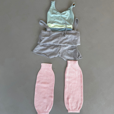 Children's outfit with top, shorts, and pink leg warmers on a gray background