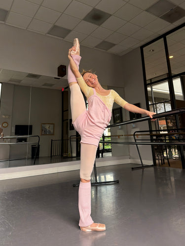 Ballerina in a pink outfit practicing ballet in a studio.